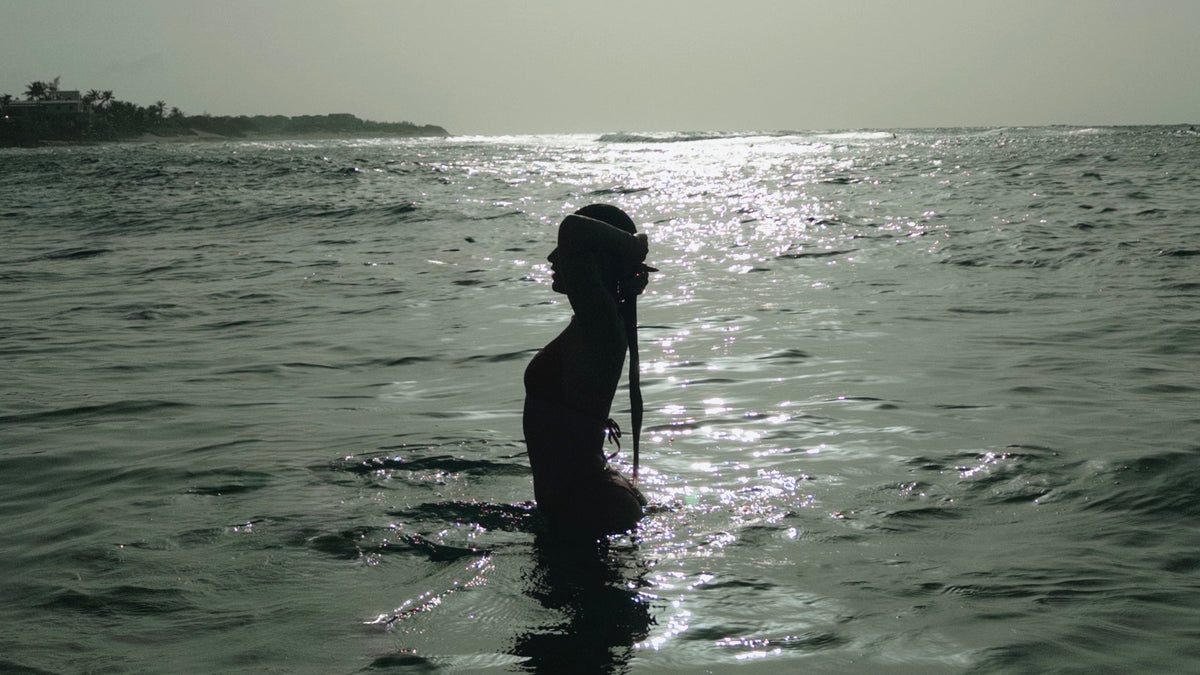 Woman wading into the ocean at dusk in Puerto Rico — the ritual and nature behind NATIVA skincare